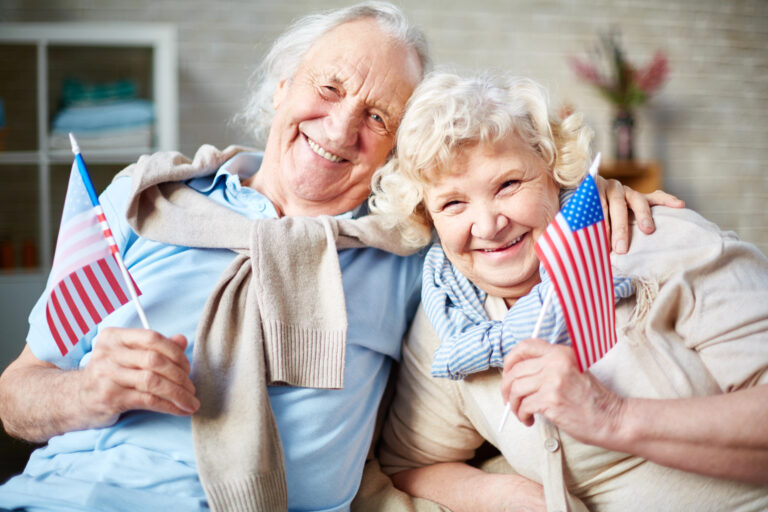 Elderly couple waving American flags -Harmony at Home Senior Care