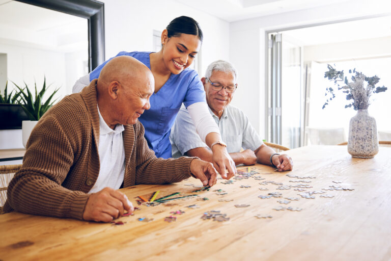 Female caregiver playing a puzzle game with 2 male seniors - Harmony at Home Senior Care