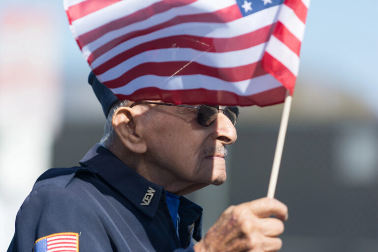 Senior veteran waving American flag - Harmony at Home Senior Care