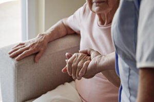 Caregiver holding a senior's hand while providing post-hospital home care and recovery support in Texas.