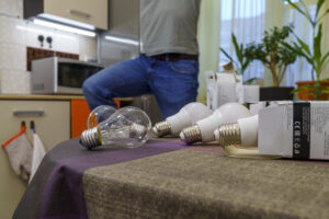 Person replacing light bulbs to improve home safety for a senior recovering after a hospital discharge in Texas.