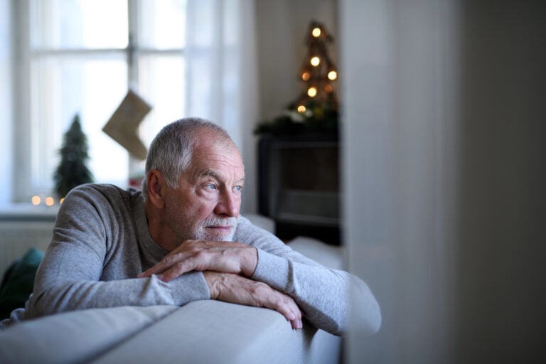 Holiday home care for seniors: Older man sitting alone at home during the Christmas season